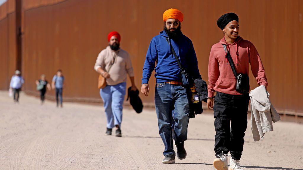 Immigrants from India walk along the border wall to turn themselves over to US Border Patrol agents on the US-Mexico border, 11 May 2023 in San Luis Río Colorado, Sonora.