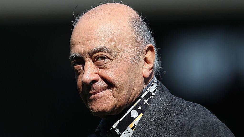 Mohamed Al Fayed, wearing an open-necked, patterned shirt and a grey pinstriped jacket, pictured in 2010 at the ground of Fulham FC, where he was chairman