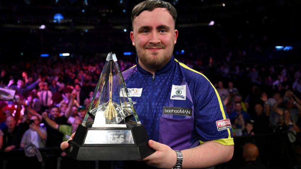 Luke Littler holding Premier League Darts trophy