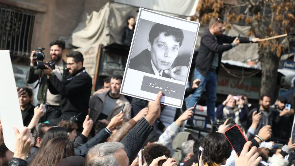 A person holds the picture of activist Mazen al-Hamada during his funeral on December 12, 2024 in Damascus, Syria