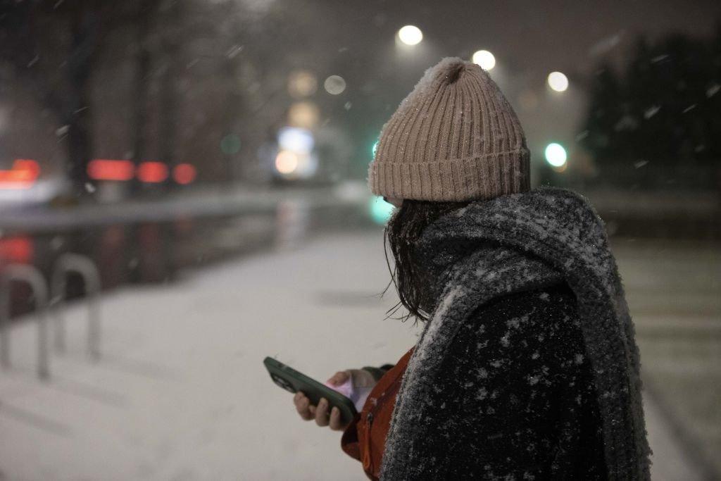 A person is seen on a snow-covered pavement during snowfall in London