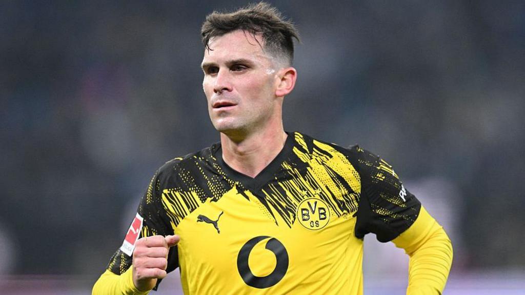 Pascal Gross holds up his fist and is wearing a black and yellow Borussia Dortmund shirt