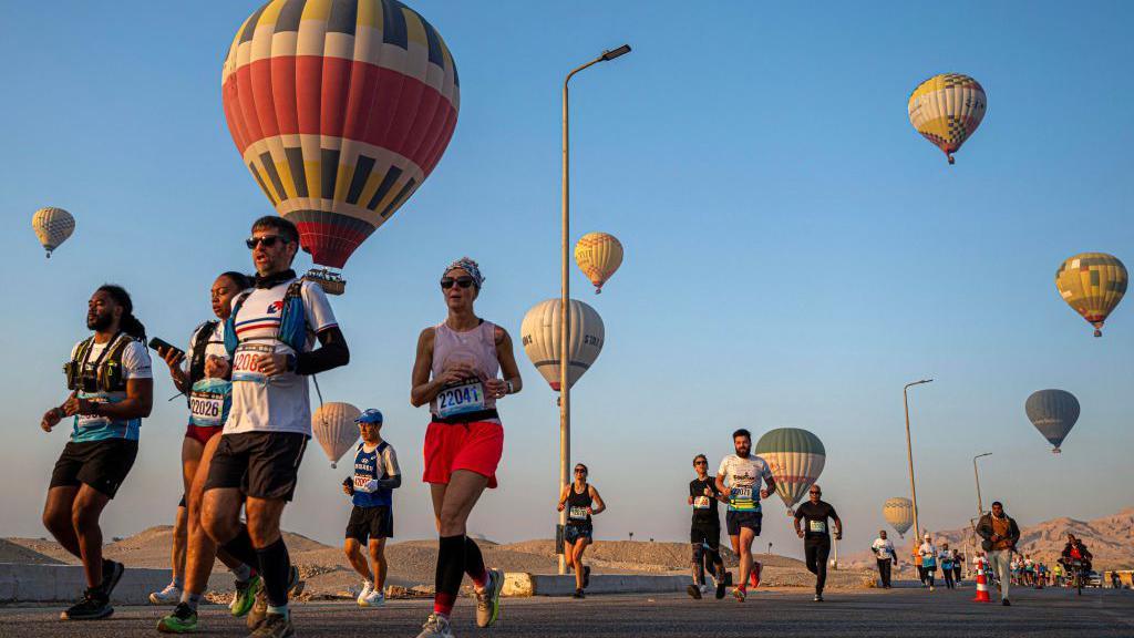 Runners start the 32nd Egyptian Marathon in front of Queen Hatshepsut's temple while hot air balloons rise over the west bank of the Nile river in Egypt's southern city of Luxor