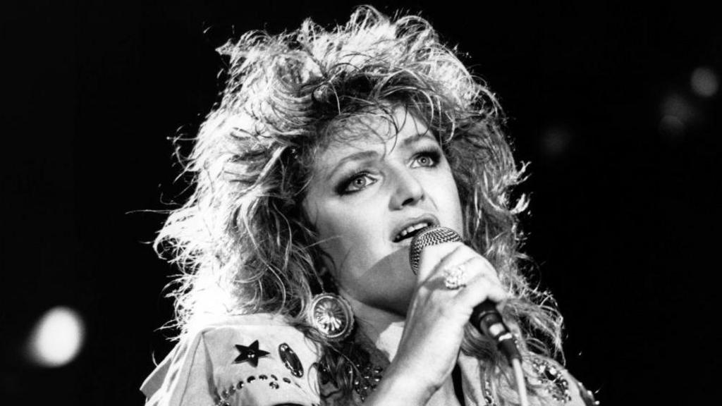 Black and white image of Bonnie Tyler singing with a microphone