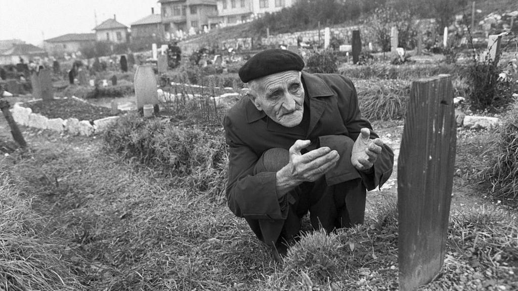 A father kneels at his son's grave in Sarajevo