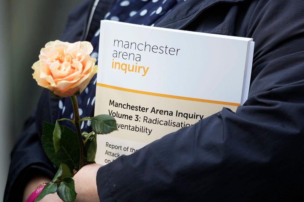 Woman holding a rose and a copy of the Manchester Arena Bombing inquiry report