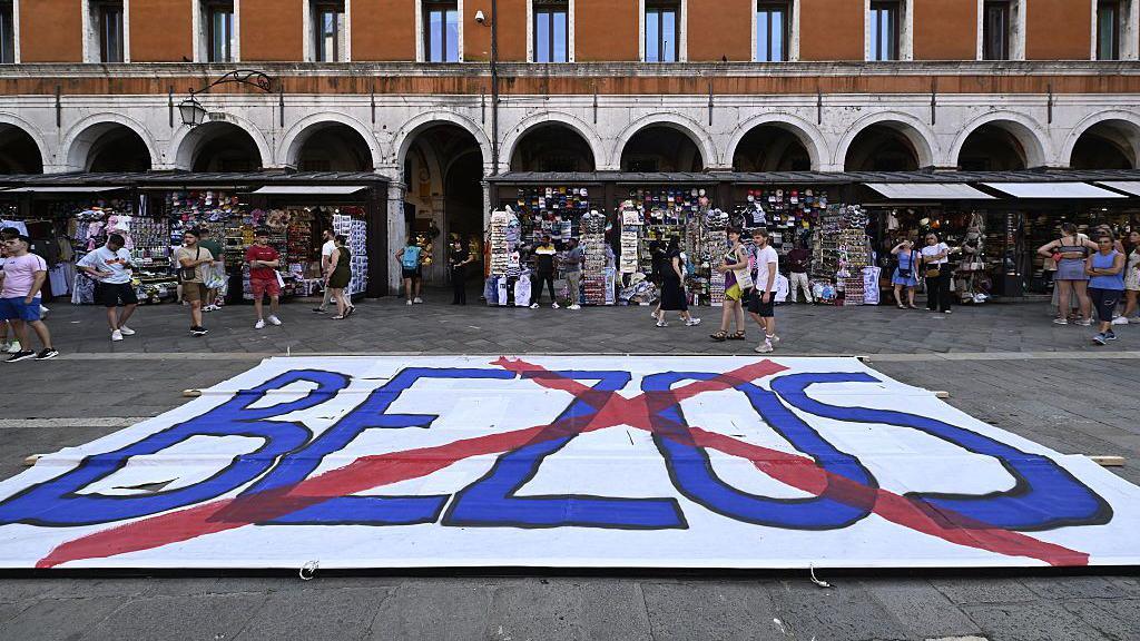 A large banner with a red cross over the word "Bezos"