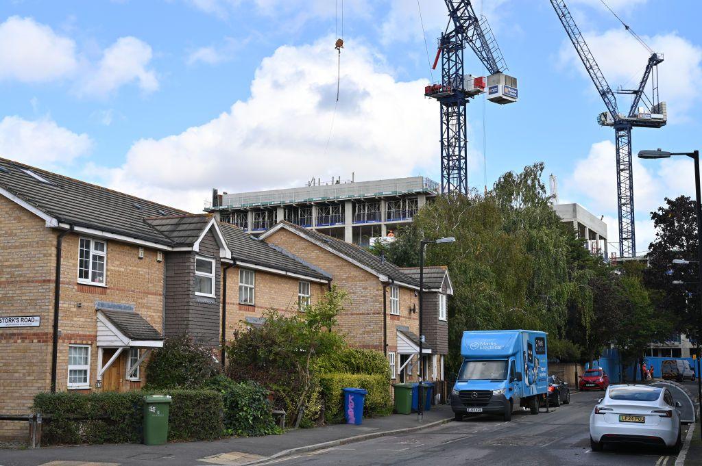 Housing with construction cranes in the background.