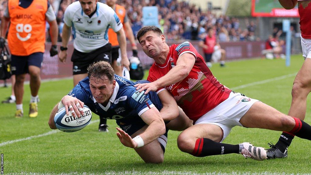 Tom Roebuck goes over for Sale's try as Ben Youngs tries to keep him out for Leicester