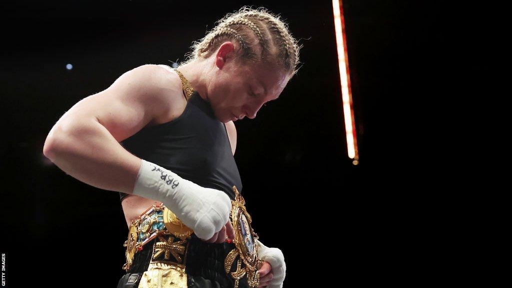 Lauren Price looks down at the British title around her waist