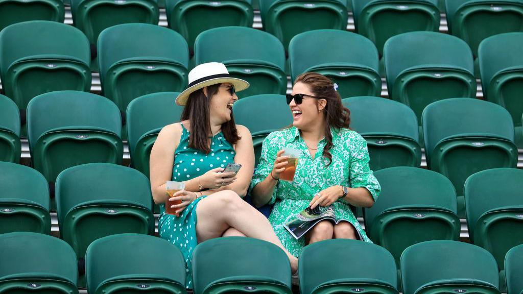 Two women sat among empty seats at Wimbledon