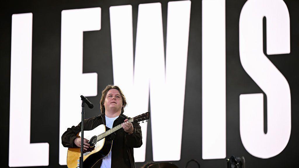Lewis Capaldi plays the Pyramid Stage, against a backdrop showing his name in bold capital letters