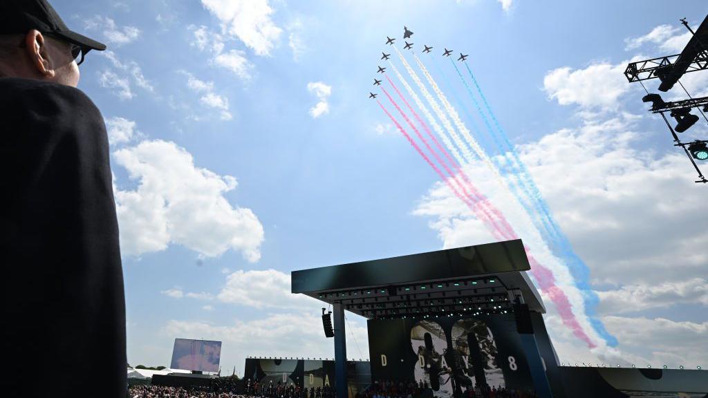 Red arrows flying over the stage of the D-Day 80 event in Southsea they are being watched by a veteran