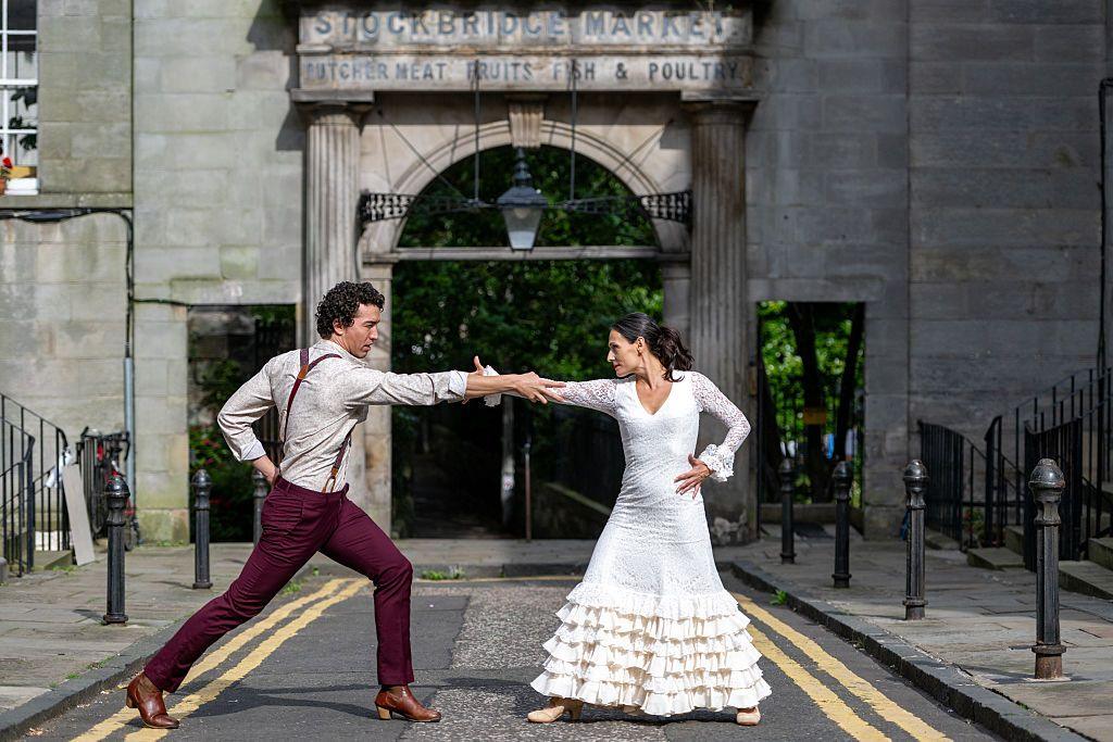 Gabriel Aragú Fernando and MarÃa Garcia Lola pose in front of the Stockbridge Market during a photocall for ‘Lola: A Flamenco Love Story’ He is wearing smart, burgundy trousers and she is in a beautiful white Flamenco dress, her hair in a pony tail. They are both looking at each other in a dance pose intensely.