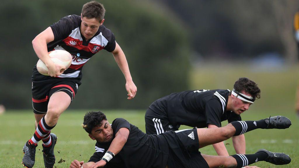 A young Cam Roigard runs away from tacklers 