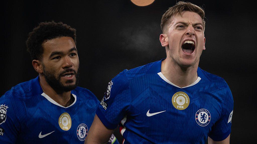 Liam Delap celebrates by cheering towards the Chelsea fans after scoring for the Blues, with Reece James coming to congratulate him