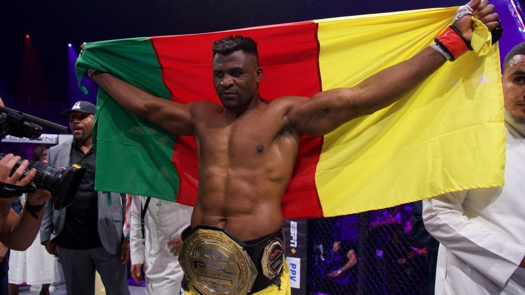 Francis Ngannou with a Cameroon flag and his PFL title around his waist