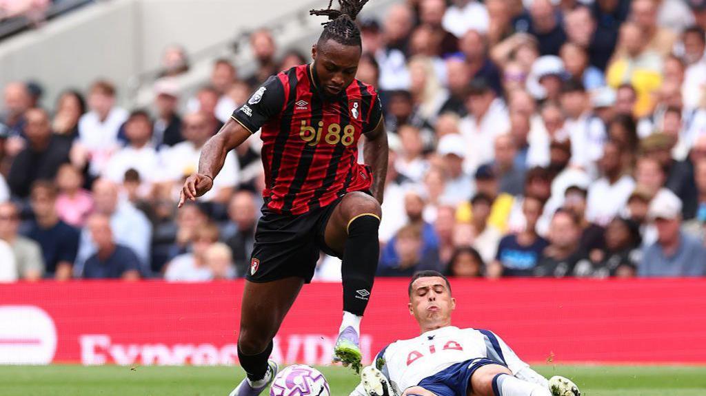 Antoine Semenyo dribbles past Pedro Porro with the Tottenham defender on the floor