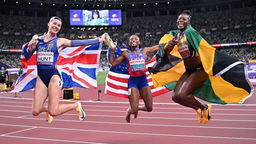 Amy Hunt, Melissa Jefferson-Wooden and Shericka Jackson jumping in the air and celebrating their win