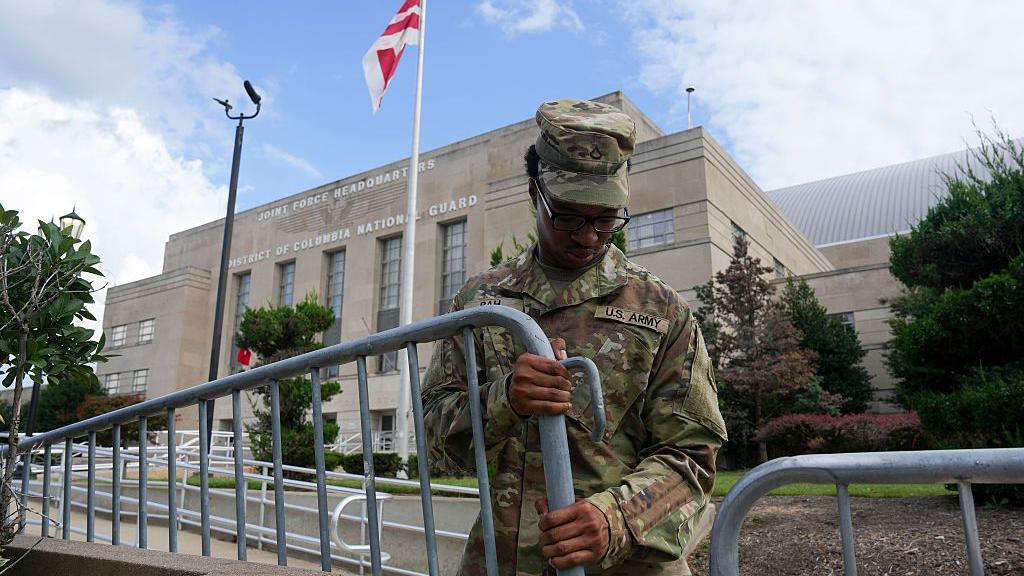 A soldier erecting a barricade outside a government building