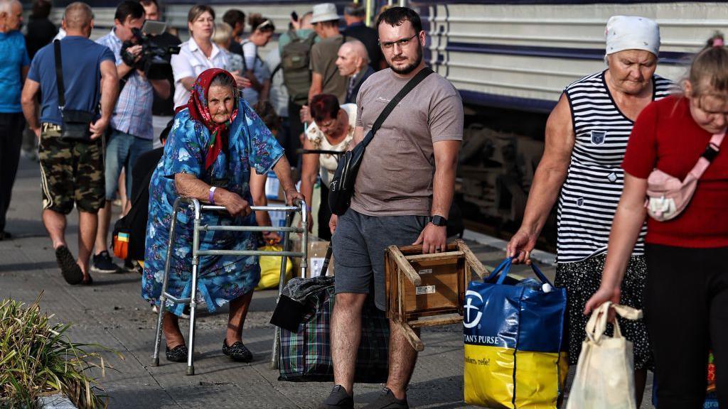 Civilians wait to board a train west in the Donetsk region, as Russian troops gain ground