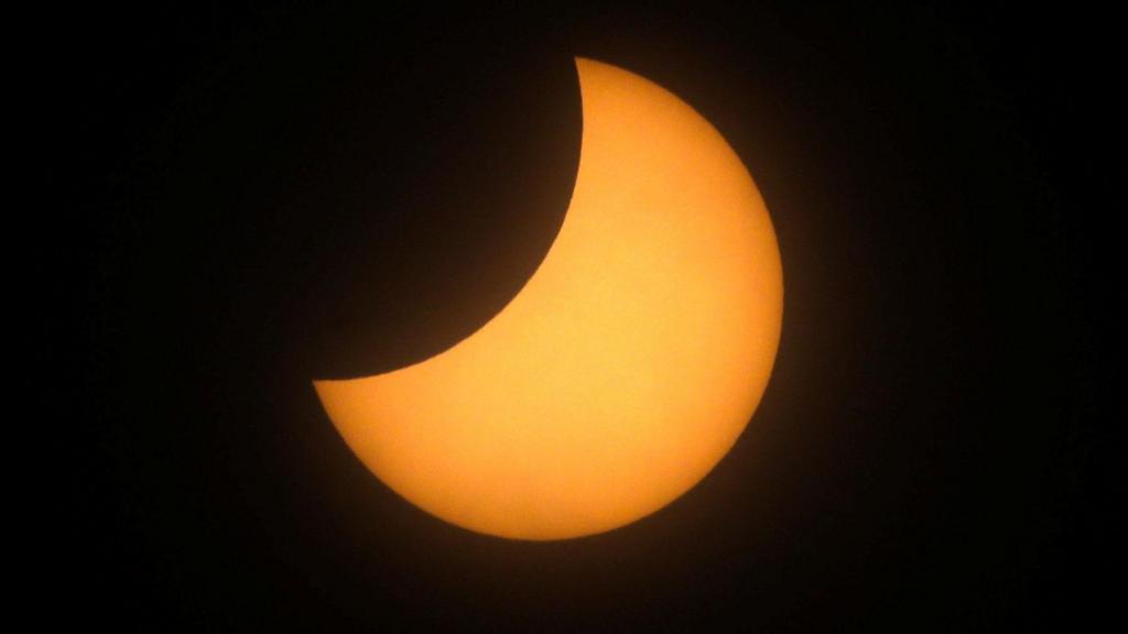 A portion of the sun is covered by the moon in a partial solar eclipse.