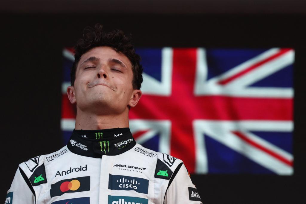 Lando Norris with his eyes closed on the Monaco podium with the Union flag in the background