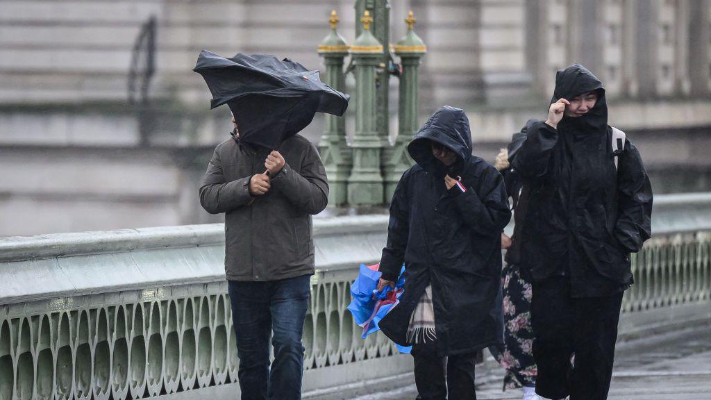 A group of people are battered by strong winds as they cross Westminster Bridge in London, United Kingdom. 
