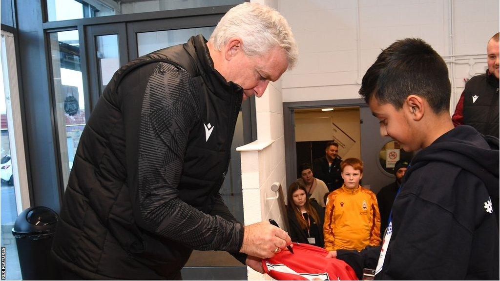 Mark Hughes signs an autograph for a young fan