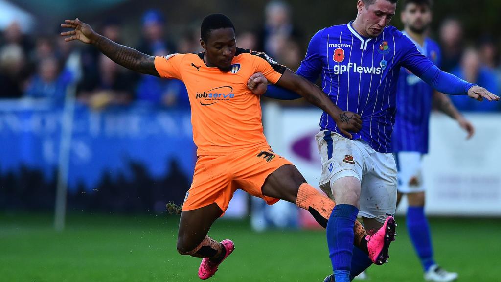 Michael Corcoran of Wealdstone is tackled by Callum Harriott of Colchester