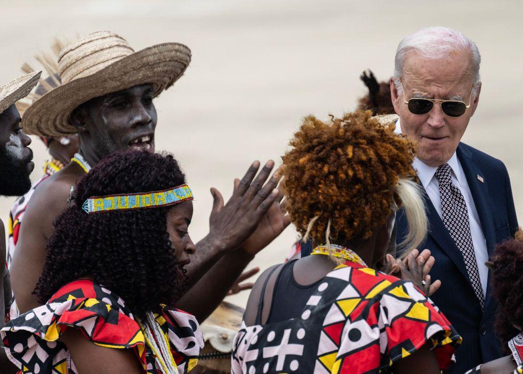 US President Joe Biden (R) reacts to dancers as he walks along the tarmac.