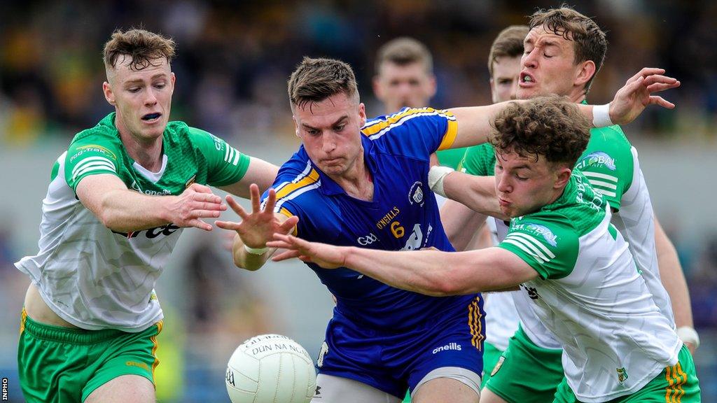 Jamie Malone in action against Odhran Doherty and Rory O'Donnell