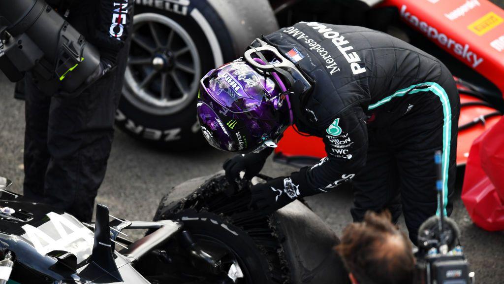 Lewis Hamilton inspects the punctured and shredded front left tyre of his Mercedes following the 2020 British Grand Prix