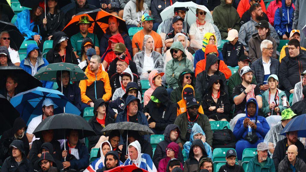 Fans watch the action at Silverstone with umbrellas and hoods up 