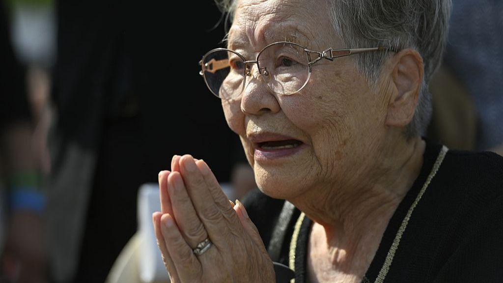 A local wearing a black shirt with glasses prays in front of the cenotaph for the victims of the world's first atomic bombing at the Peace Memorial Park