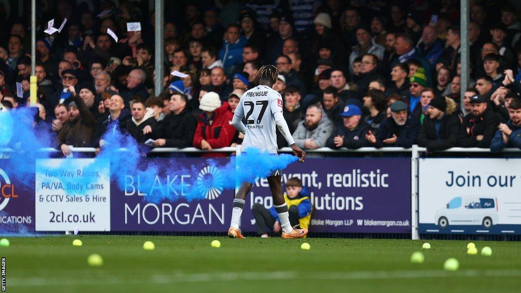 Reading's Amadou Mbengue removes a flare from the pitch