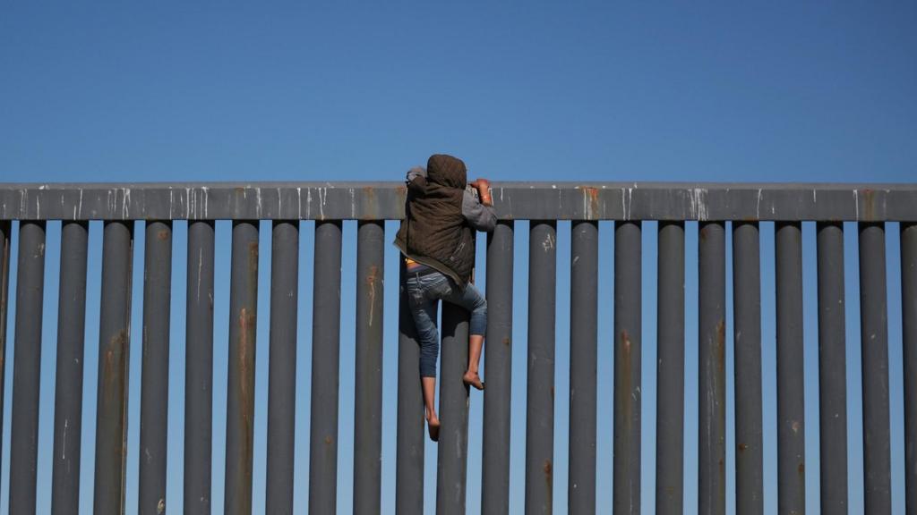 A person crossing the US-Mexico border wall