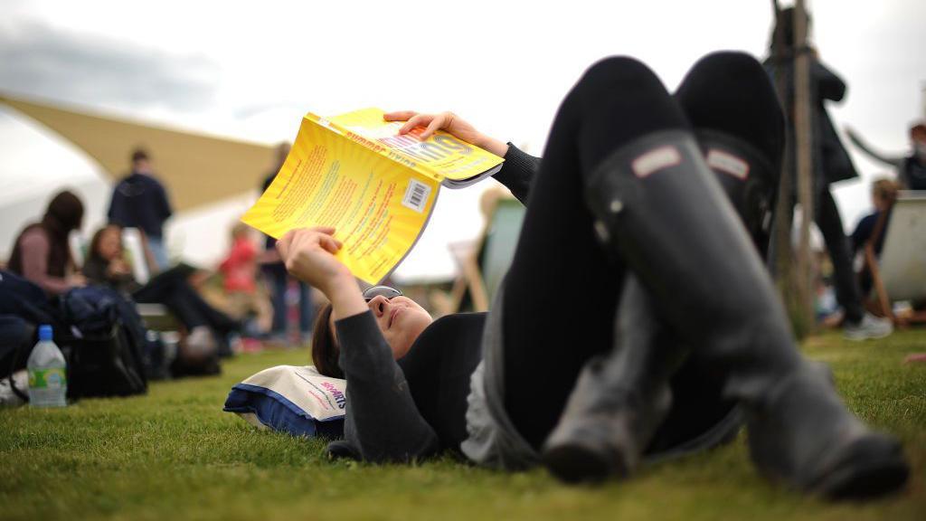 A person reading a book at Hay Festival