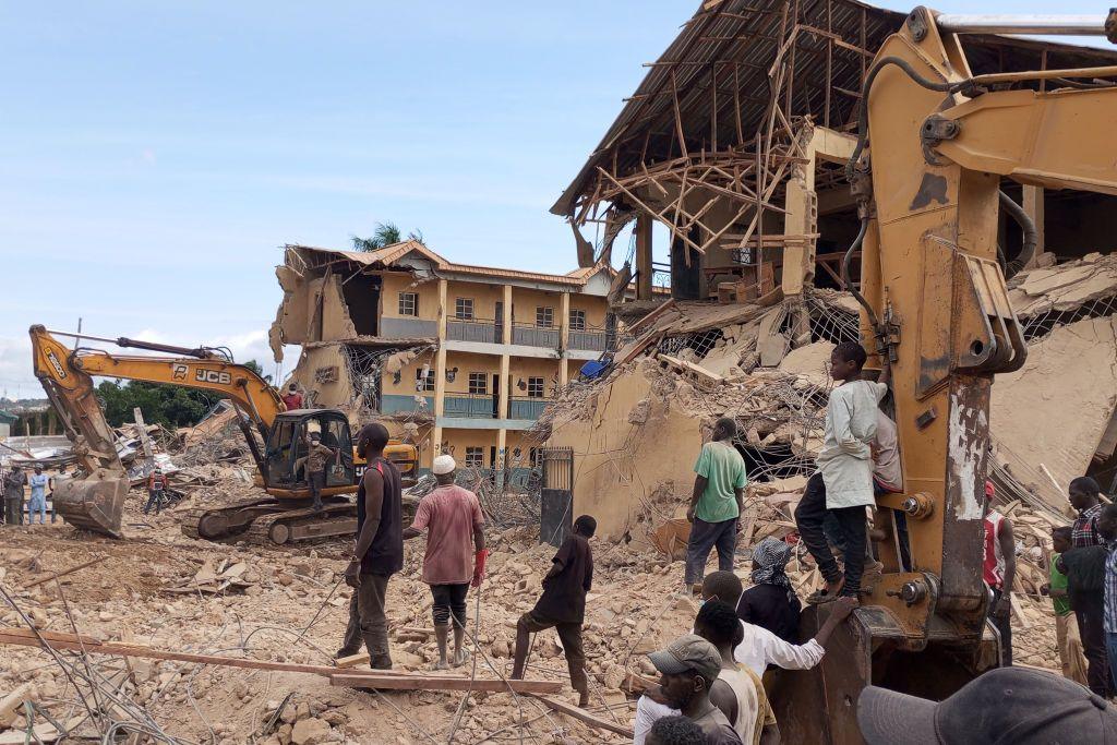 People and excavators on site Saints Academy in Jos.