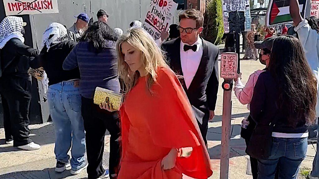 Attendees walking past pro-Palestinian protesters