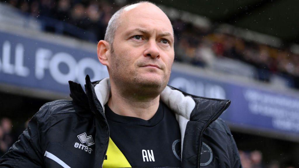 Alex Neil in front of a football stand.