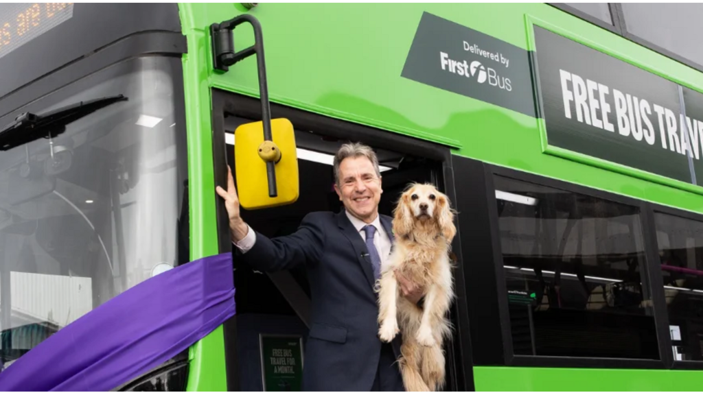 Dan Norris holding his dog Angel on a Green bus