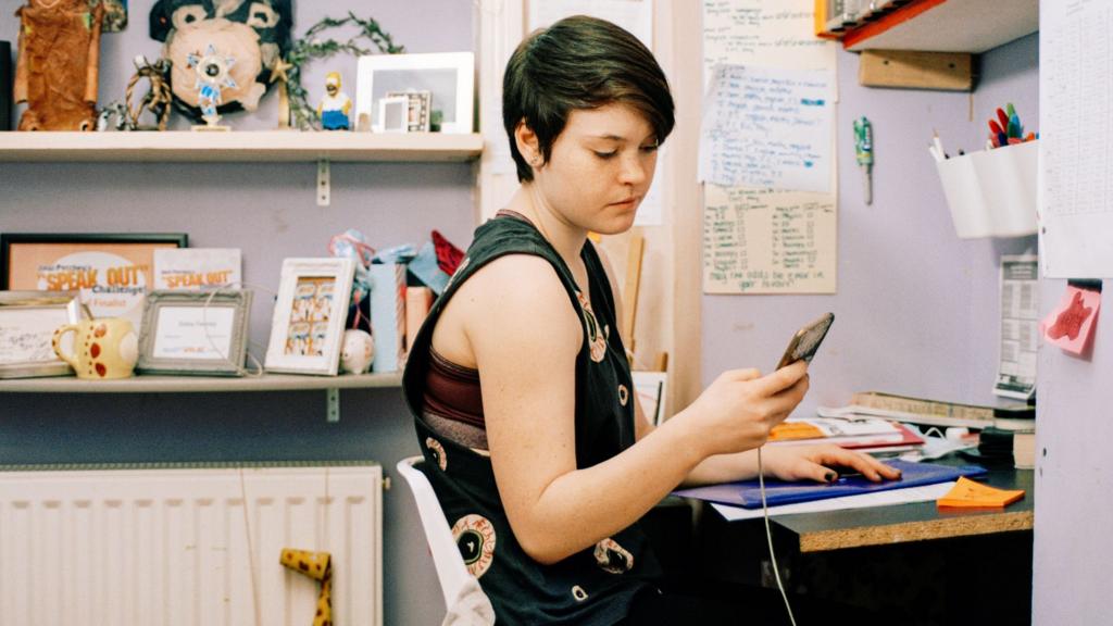 A teenager sits at her desk texting