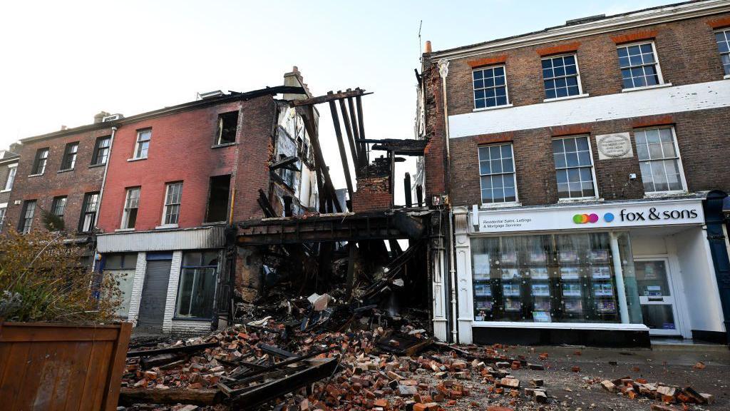 A general view of the scene of the fire, on December 09, 2024 in Dorchester, England, with bricks spilling out into the street. 