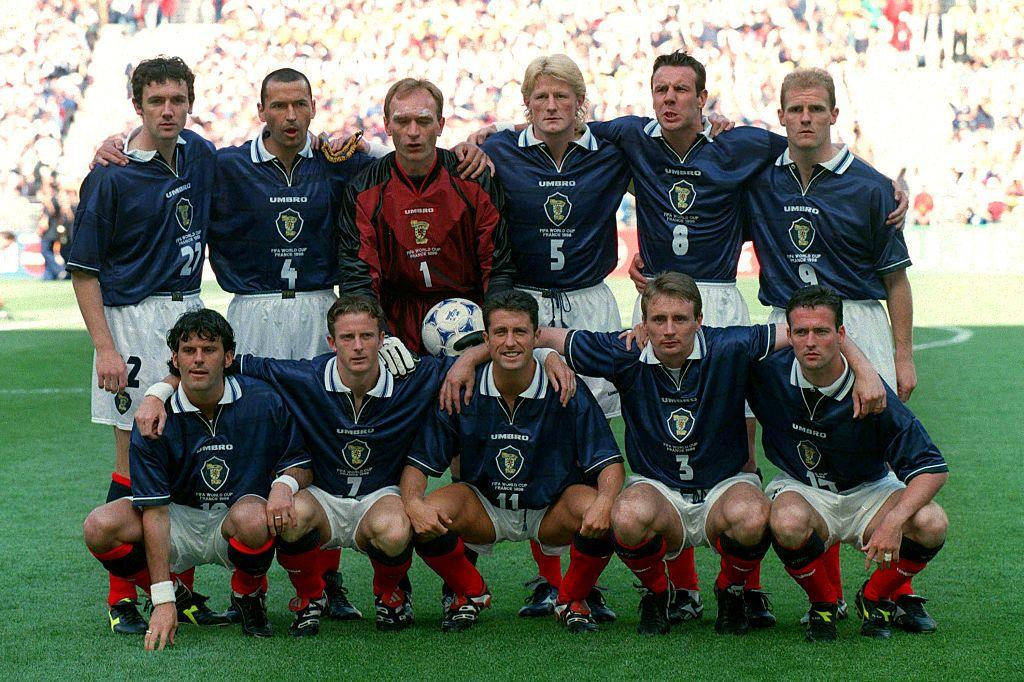 The whole squad crouch and stand on the pitch.