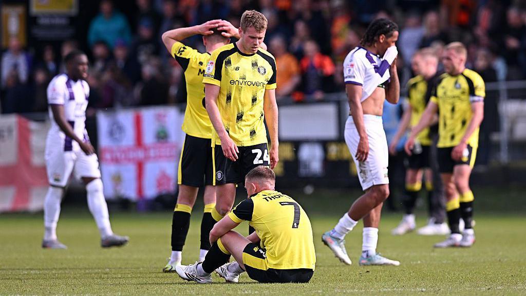 Harrogate players sink to the turf and put their hands to their heads after relegation