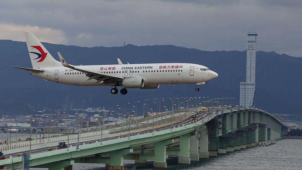 A plane flying past a bridge with the words China Eastern written on it