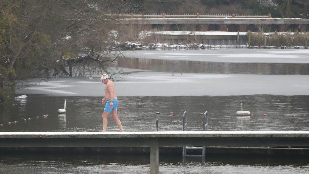 A man walks down the decking in one of the ponds of a cold day