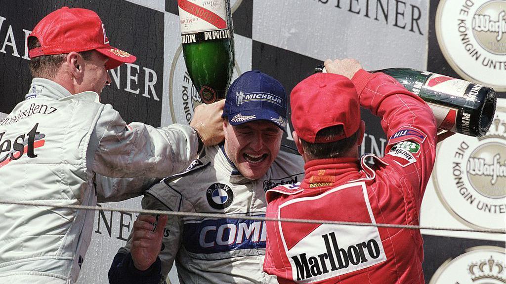 Ralf Schumacher of Germany has champagne poured all over him for winning the race from McLaren-Mercedes driver David Coulthard (left) of Great Britain and Ferrari driver Rubens Barrichello in 2001