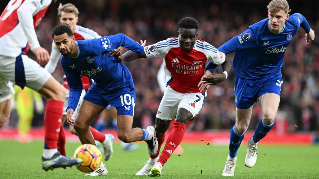 Bukayo Saka and Everton players challenge for the ball